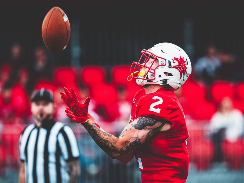 Football player in red uniform catching a ball with a blurred stadium background